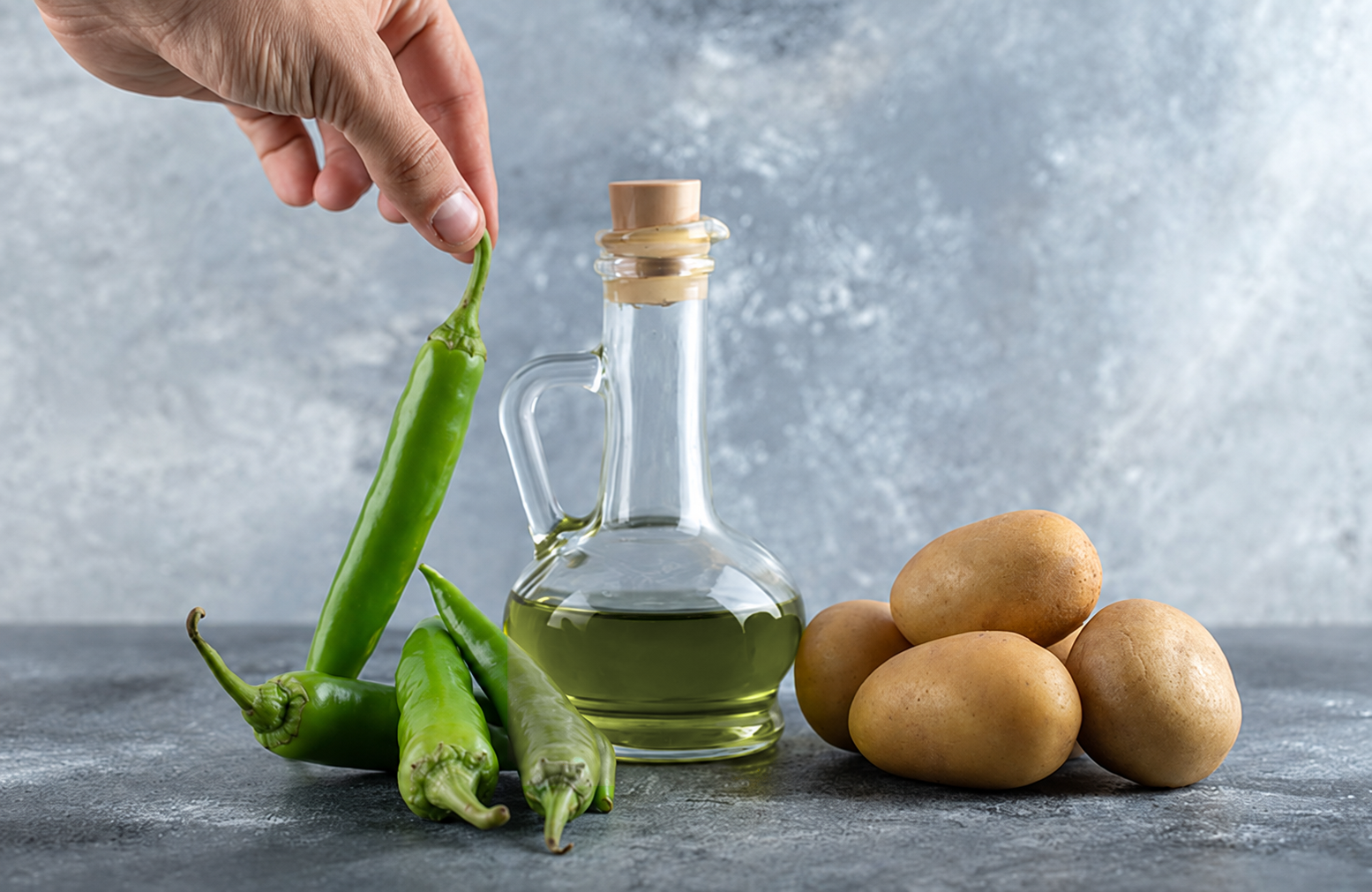 Aceitera de vidrio junto a verduras: evitar el calor alarga la caducidad del aceite